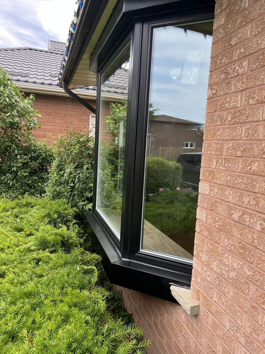 Side view of the finished black bay window against the brick wall of the Professor's Lake Parkway home in Brampton