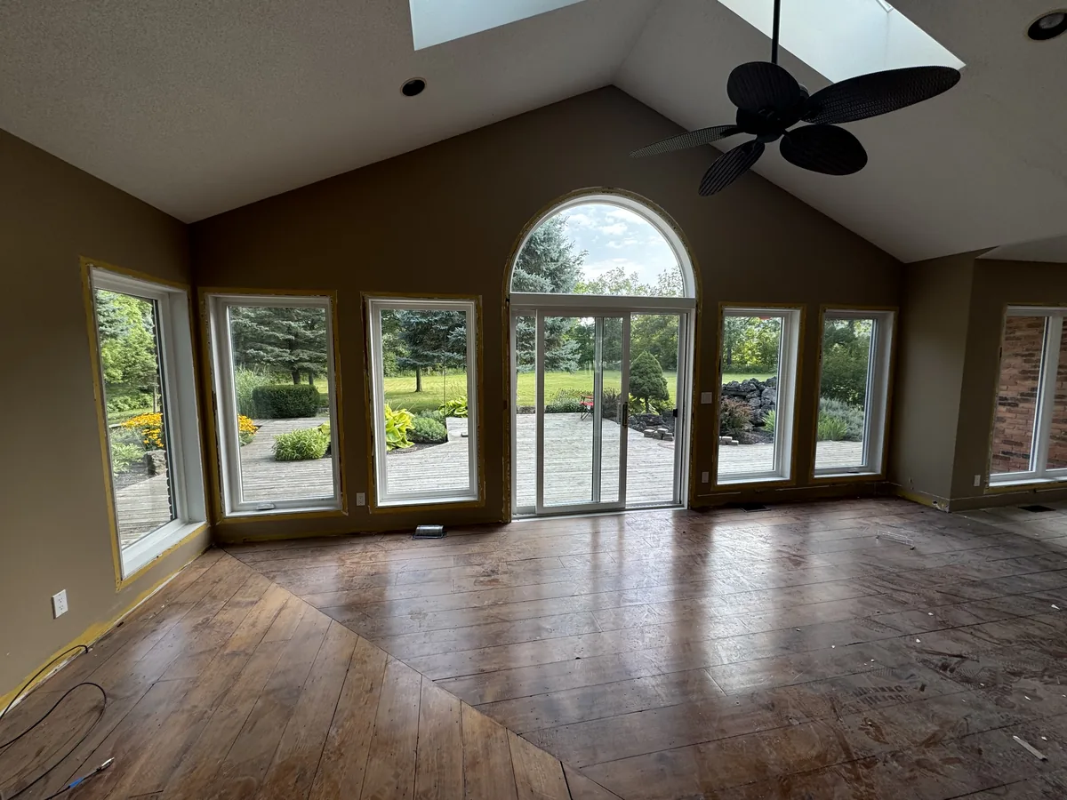 The estate's vaulted great room with its new wall of white windows and arched transom overlooking the grounds