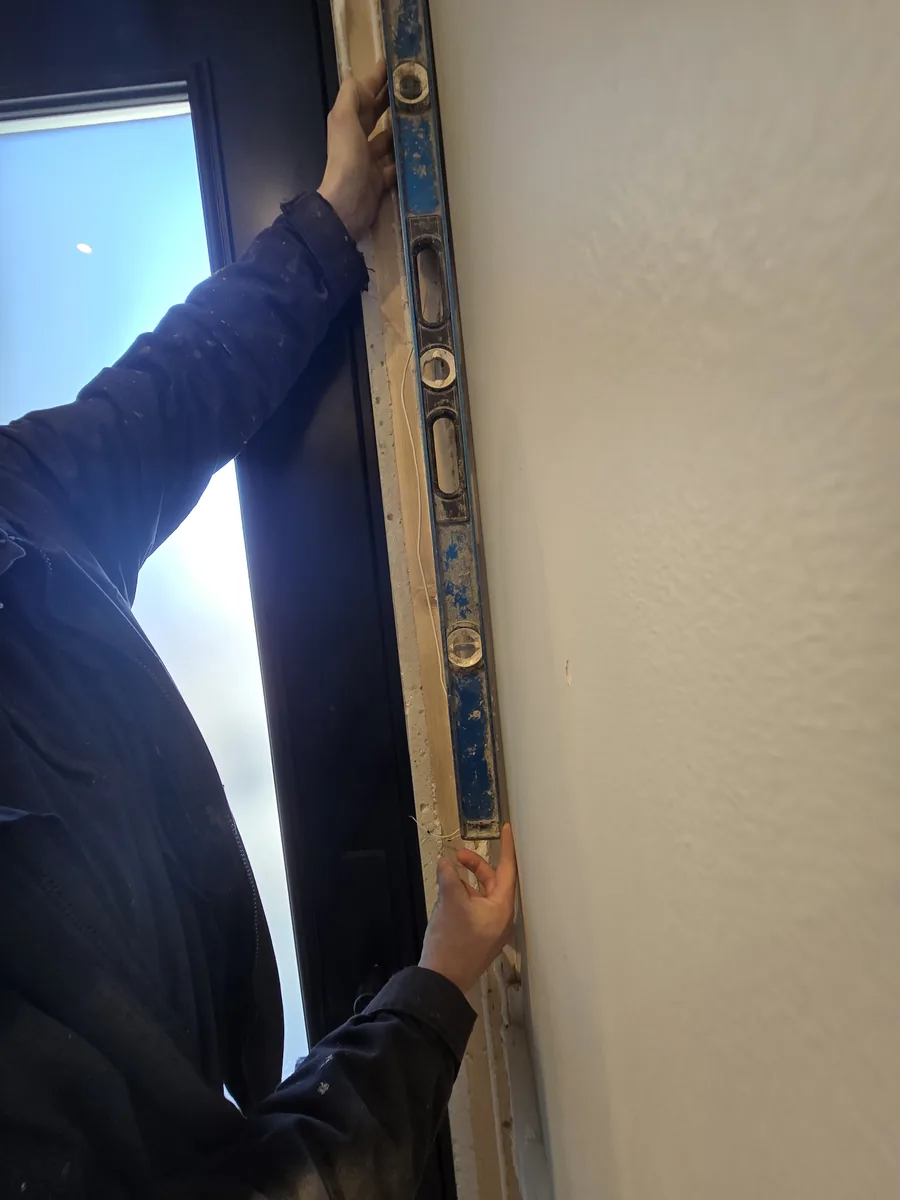 Installer leveling the new eight-foot door frame in the enlarged entry opening