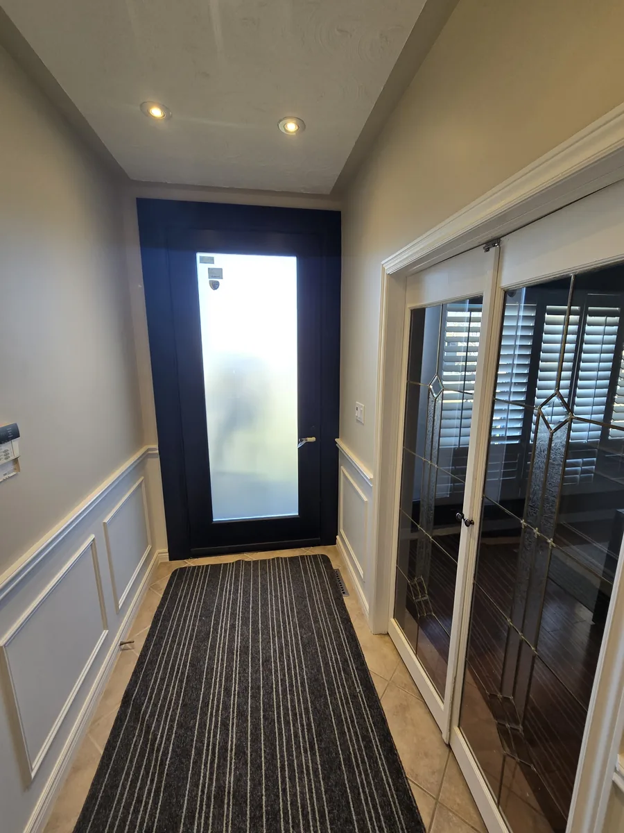 Eight-foot frosted-glass entry door seen from inside the Stoney Creek home, with wainscoting and french doors