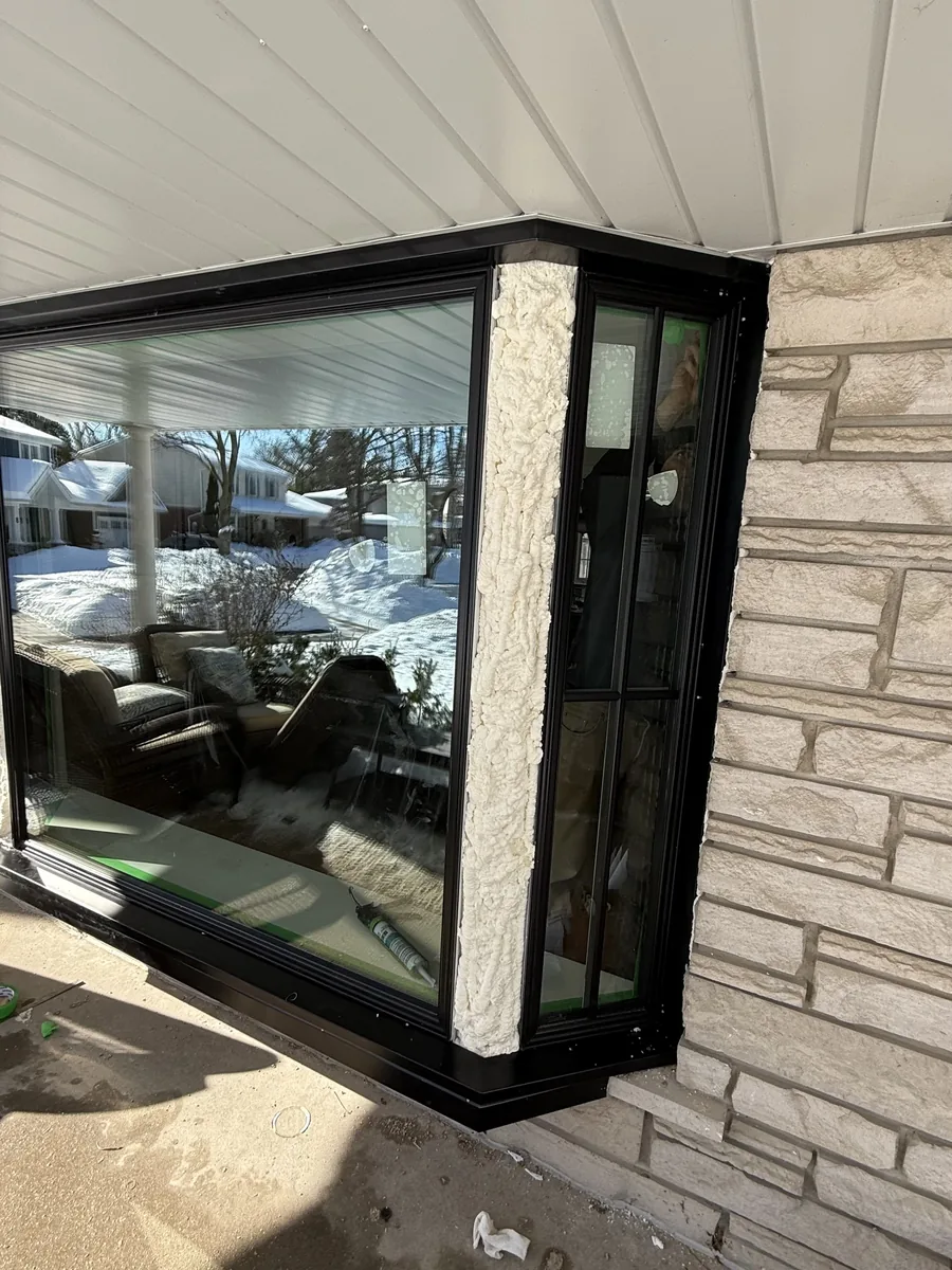 The finished black bay window with colonial grills, seen up close against the stone
