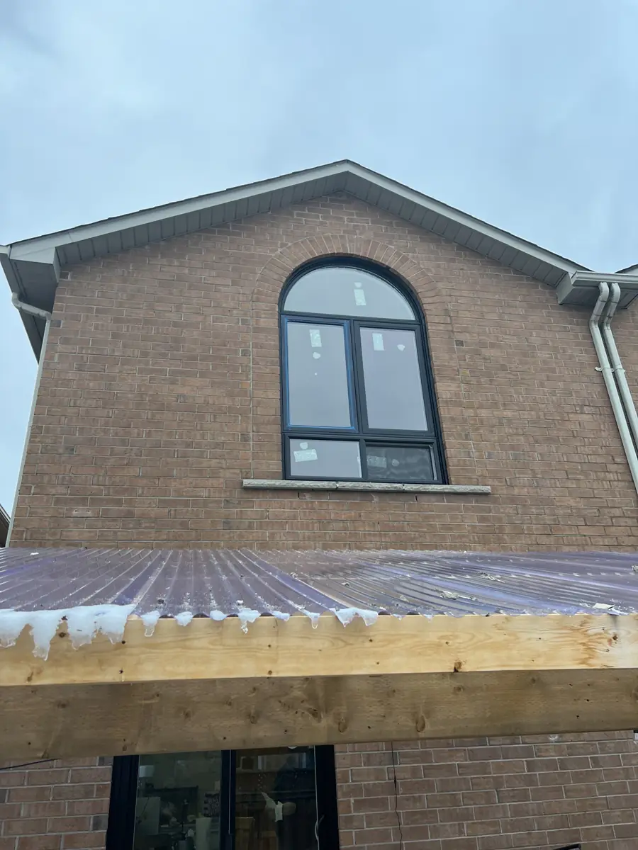 Custom black arched fixed window following the brick arch of a Mississauga home after replacement