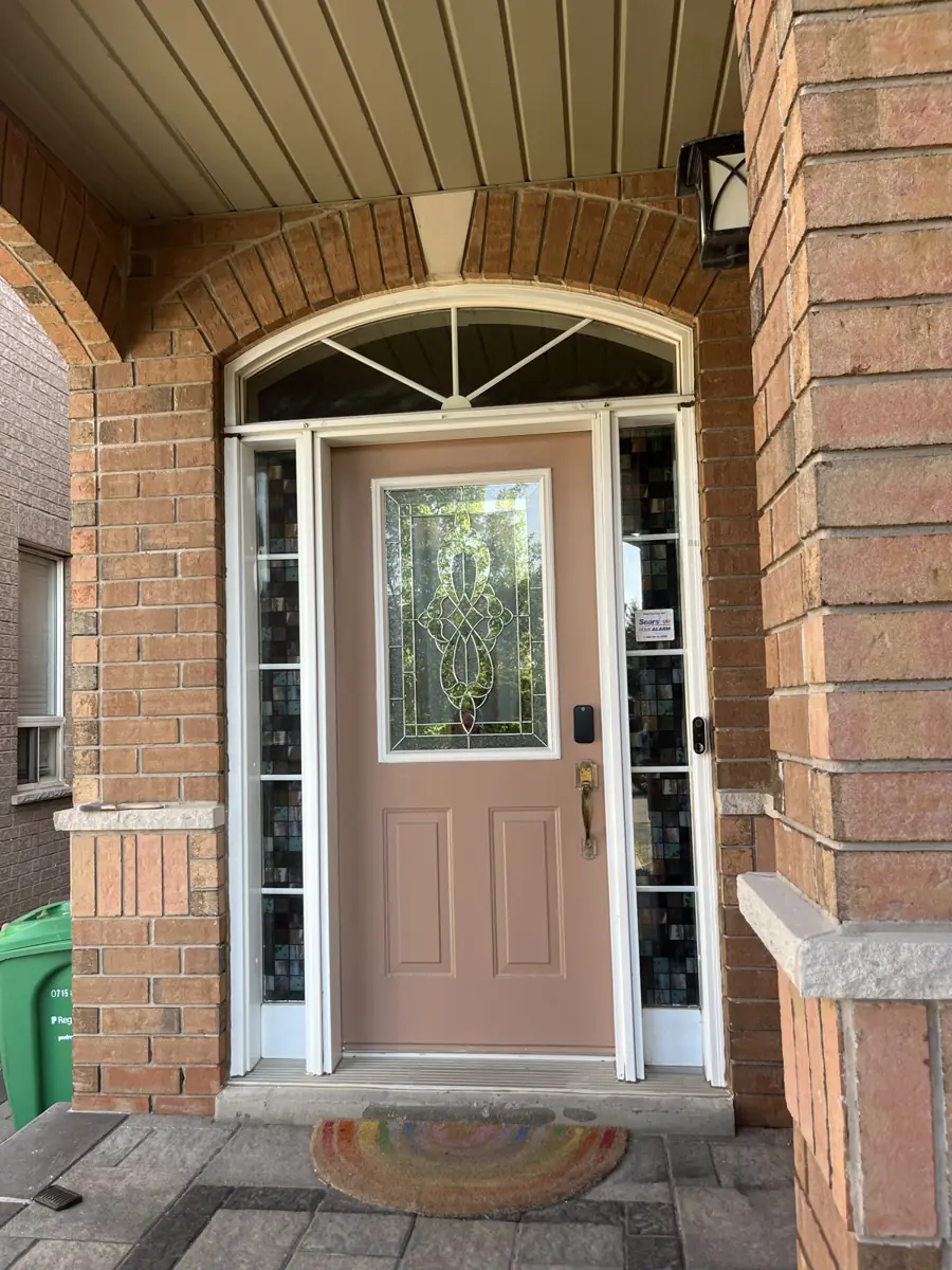 Original entry door with sunburst arched transom on a Mississauga brick home before replacement