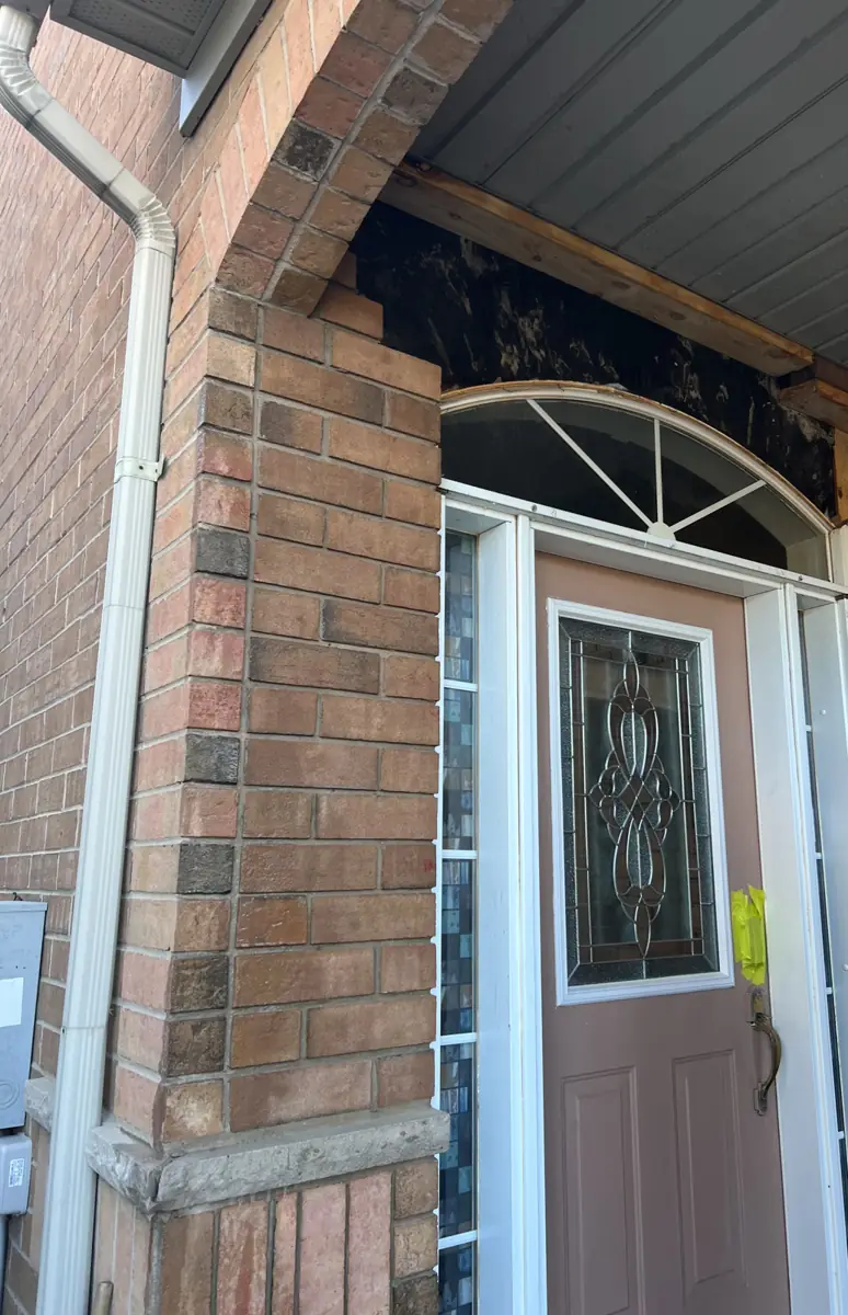 Entry opening cut wider with structural support exposed above the arch during door replacement in Mississauga