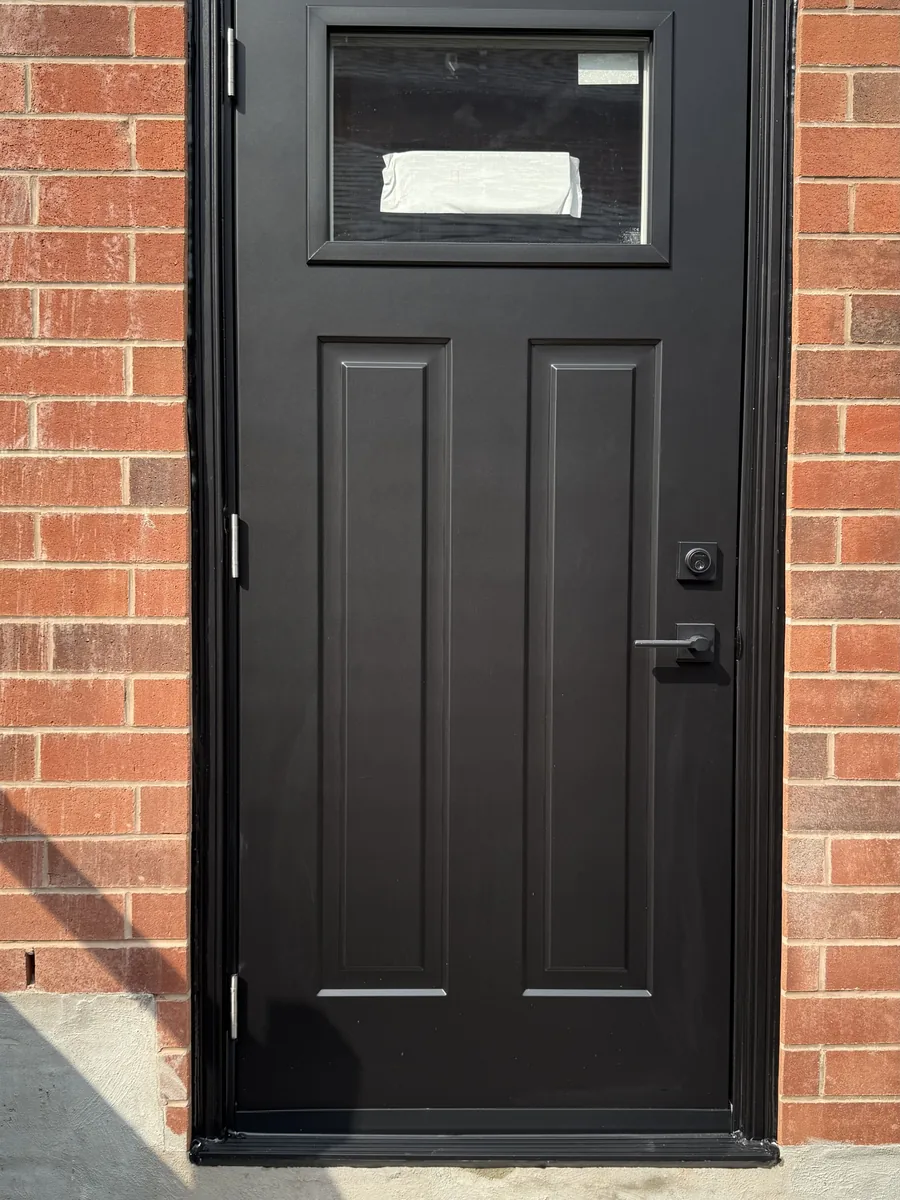 A second black craftsman-style door set into the red brick of the Newmarket home