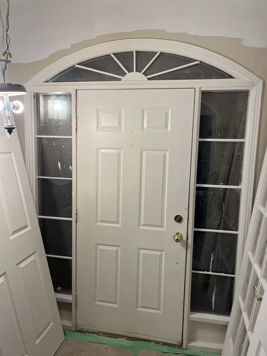 Original white entry door with sunburst transom in the Oakville home before replacement