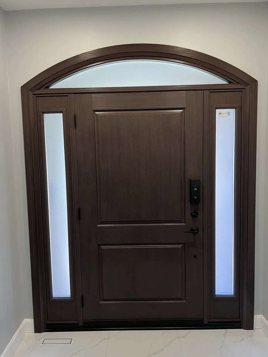 Finished mahogany entry door with arched transom and frosted sidelites seen from inside the Oakville home