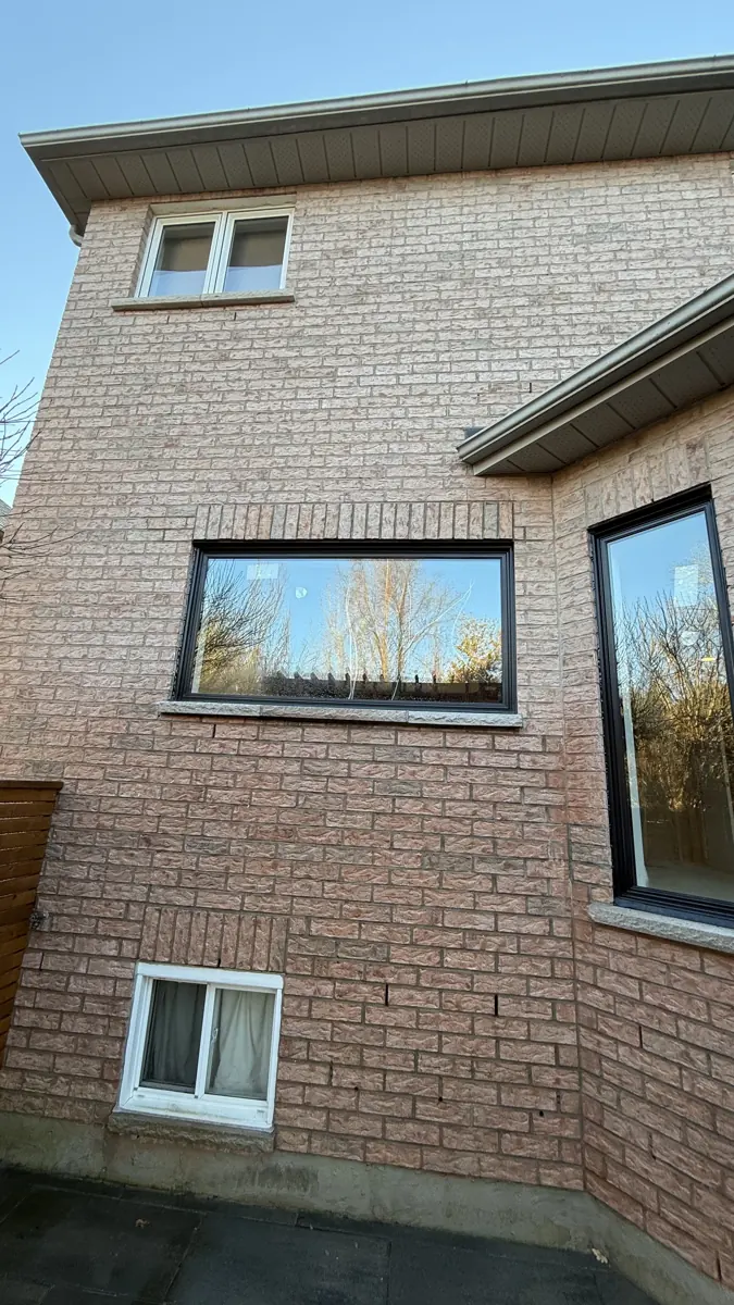 Enlarged window opening finished with a black picture window on a brick home in Pickering