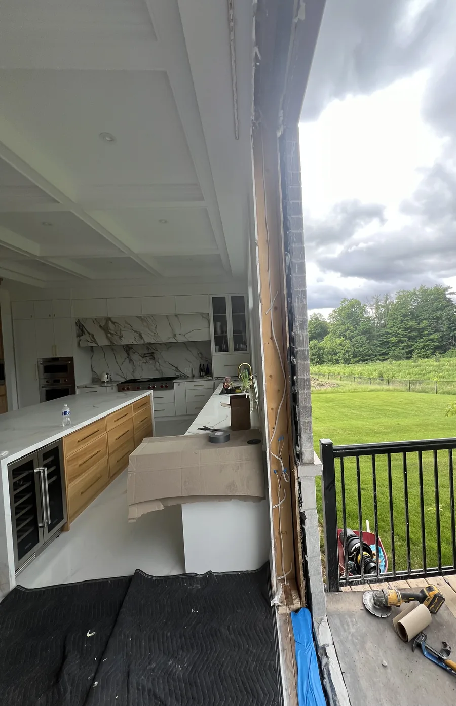 Kitchen wall opened to the deck during door replacement at the Kleinburg estate, marble island and coffered ceiling visible