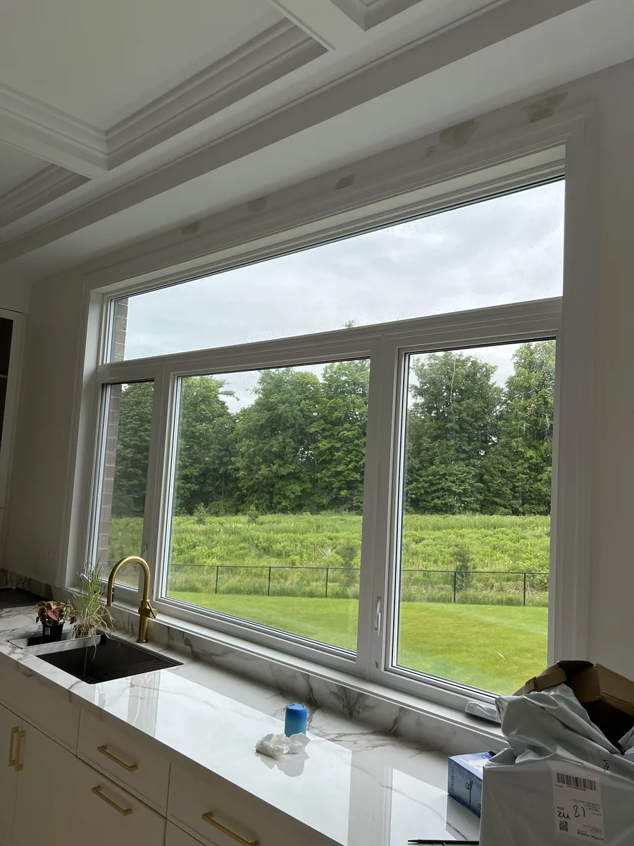 Finished ten-foot kitchen window over the marble counter with a ravine view, white interior frames