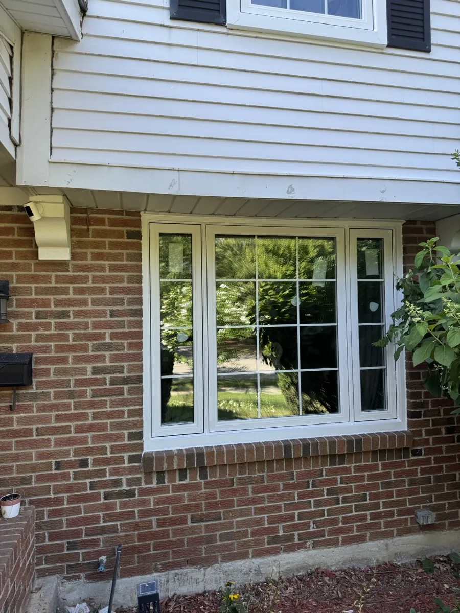 Black-framed replacement window installed in a brick home